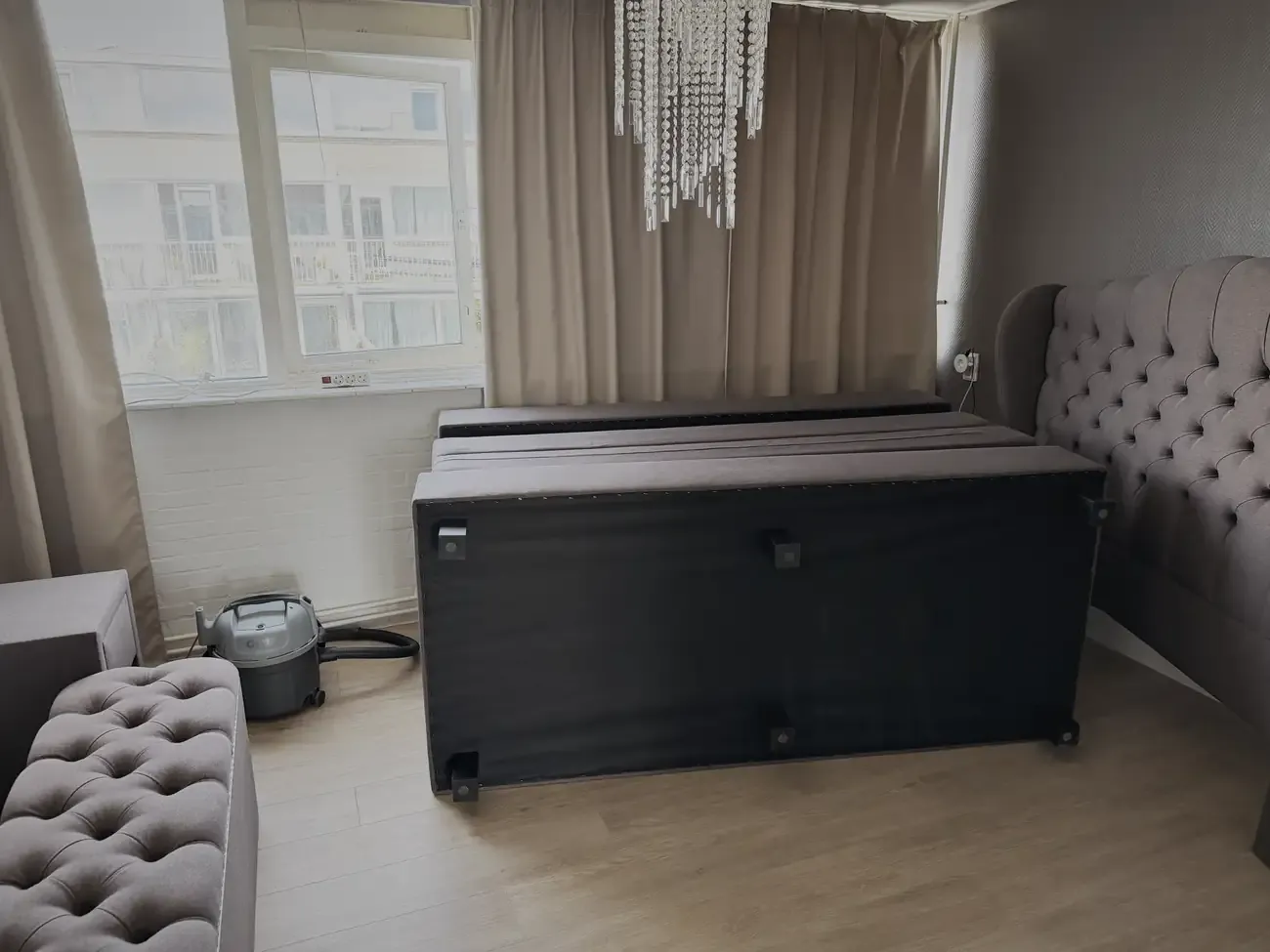 Het bed uit elkaar, de boxsprings op hun kant tegen het hoofdbord