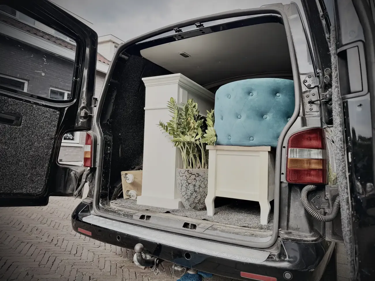 De bus achterin volgeladen met het tv-meubel, een plant en de poef