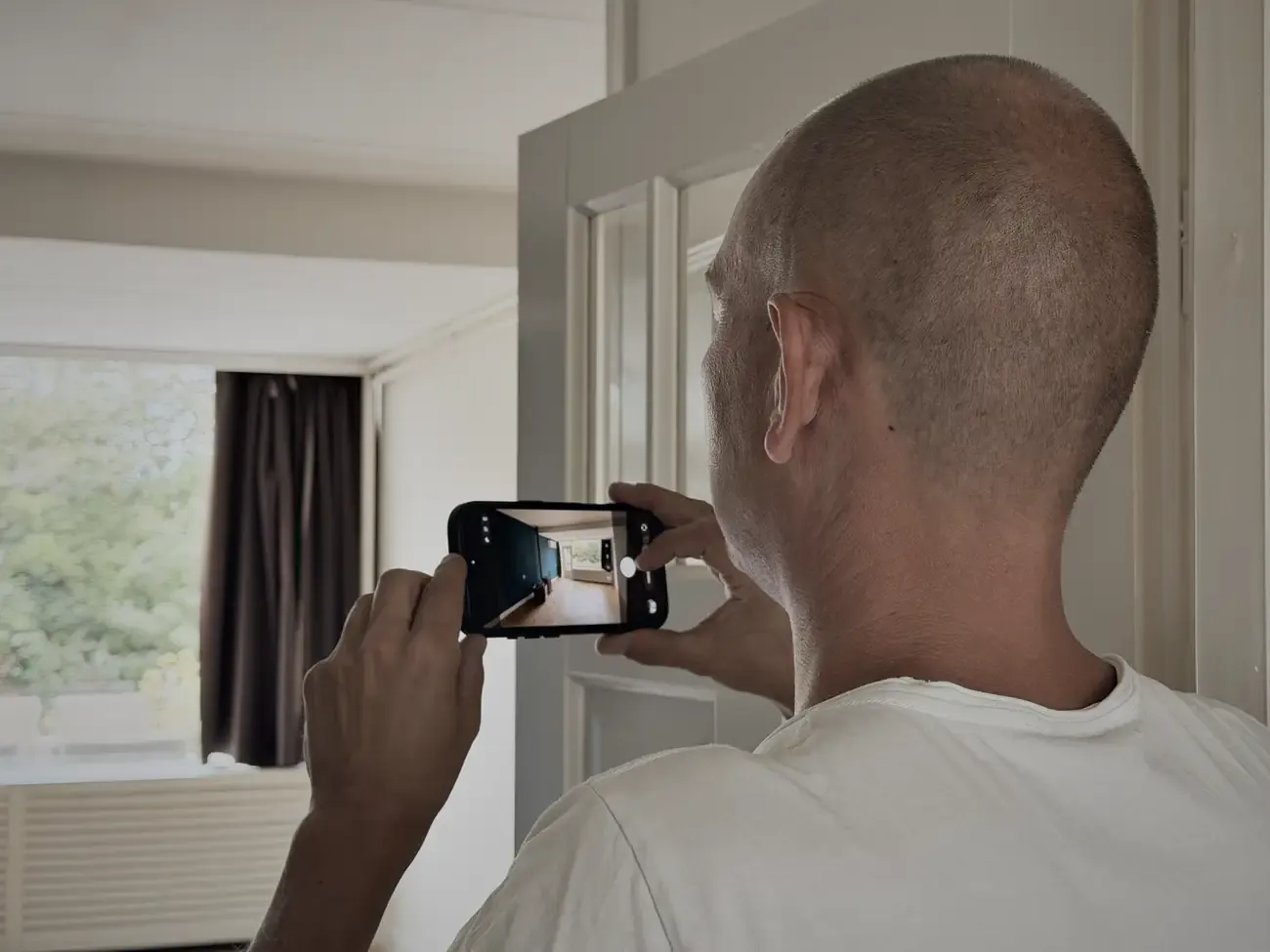 Wesley fotografeert met zijn telefoon een lege kamer
