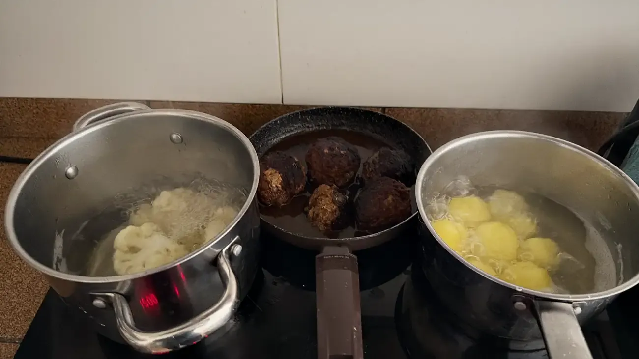 Drie pannen op het fornuis: bloemkool, gehaktballen in de jus en aardappelen