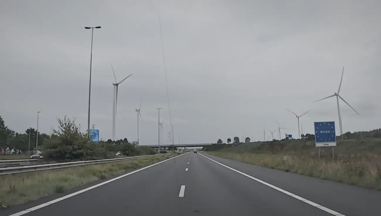 De snelweg richting de grens, grijze lucht en windmolens