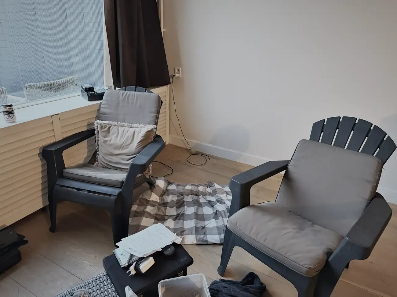 Twee tuinstoelen met een geblokte plaid in de lege woonkamer
