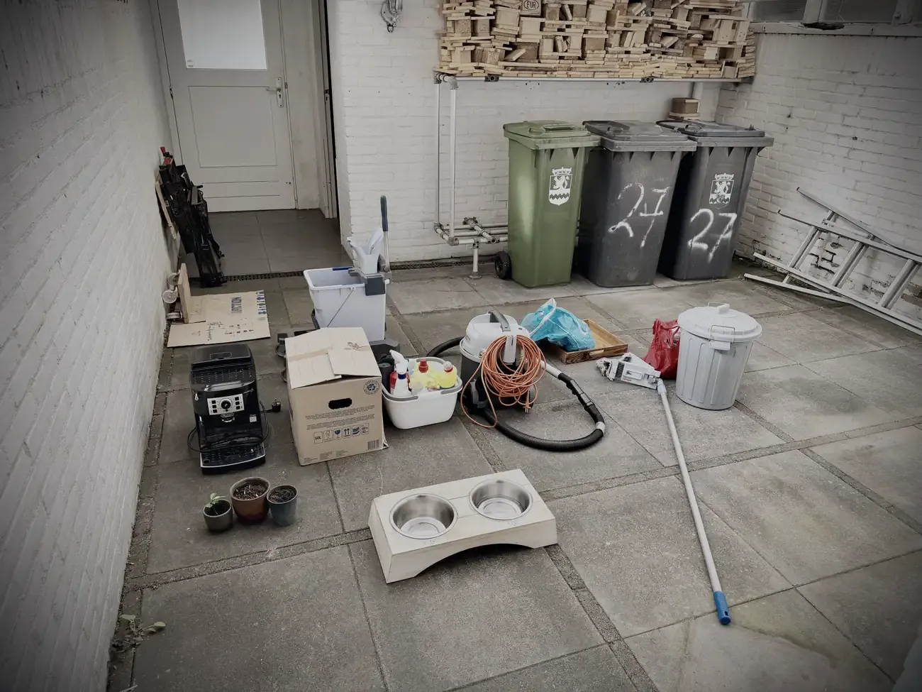 De laatste spullen in de voortuin: containers, koffiemachine, stofzuiger en de bakken van Mo