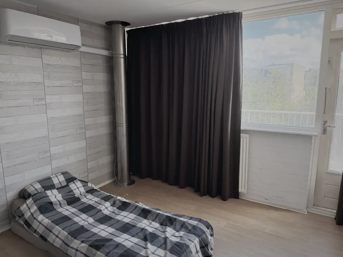 Een matras op de grond in het oude kantoor, met een geblokte deken erover
