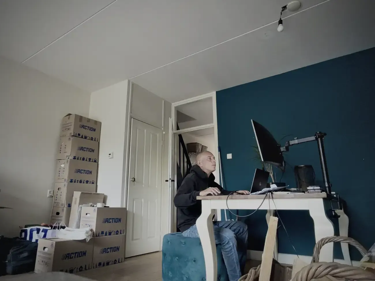 Wesley aan de eettafel tussen de dozen, werkend op een poef