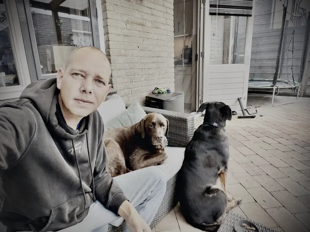 Wesley op de grond in de tuin, met Mo en Lola naast zich