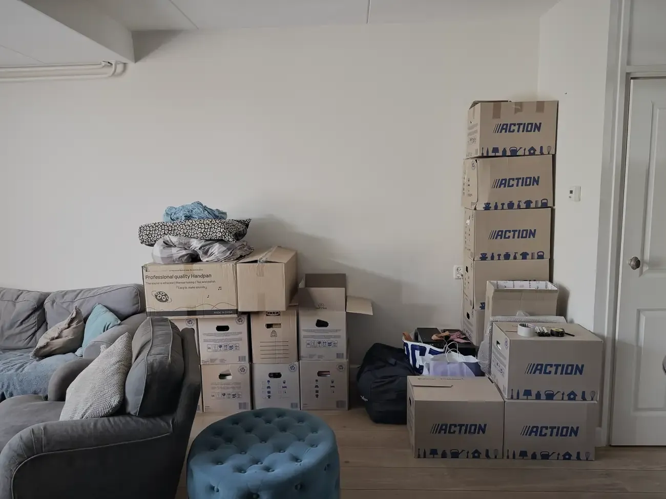 De woonkamer met de bank en stapels dozen ertegenaan