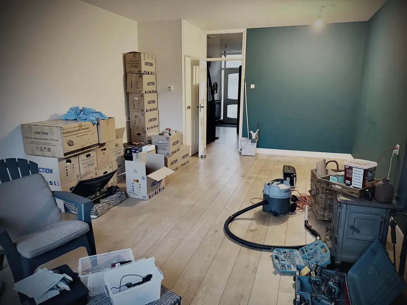De woonkamer zonder meubels, met stapels verhuisdozen tegen de muur